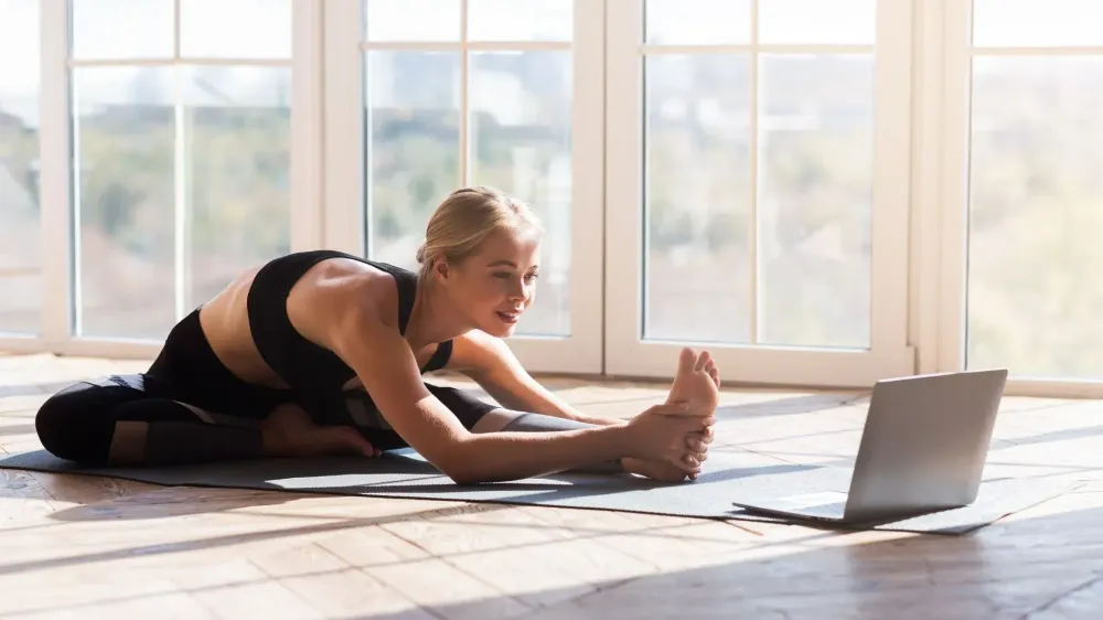Woman streaming a workout on a laptop at home